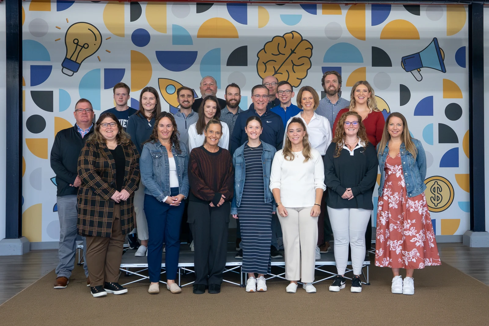 Xavier Athletics training participants gathered in front of the colorful interior mural at The Loop.
